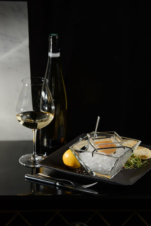 Pike fish caviar, on ice, with croutons, lemon, on a transparent dish, on a dark backgroundの写真素材