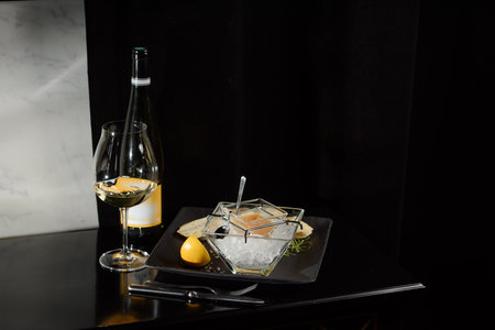 Pike fish caviar, on ice, with croutons, lemon, on a transparent dish, on a dark backgroundの写真素材