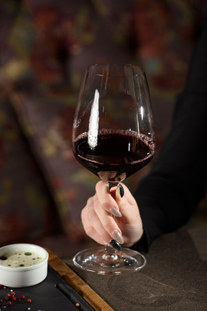 Woman sitting at a table in a restaurant. He is holding a glass of red wine and eating a steakの写真素材