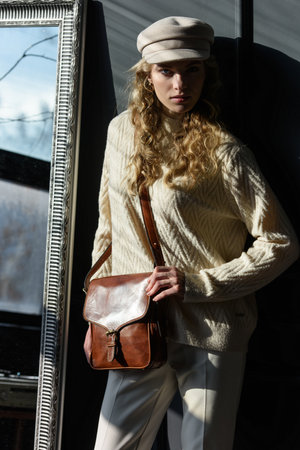 beautiful curly blond hair woman posing with a small brown near grey wallの写真素材