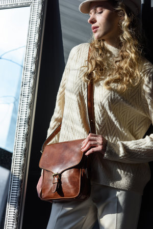 beautiful curly blond hair woman posing with a small brown near grey wallの写真素材