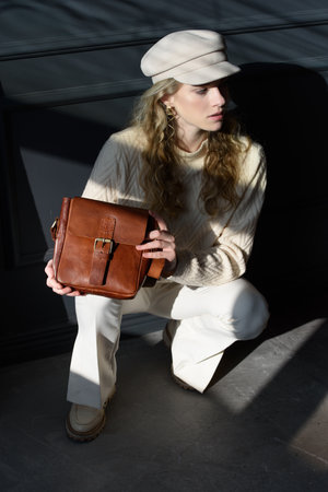 Studio portrait of beautiful woman with a curly blond hair holding brown bag, posing on gray background.の写真素材