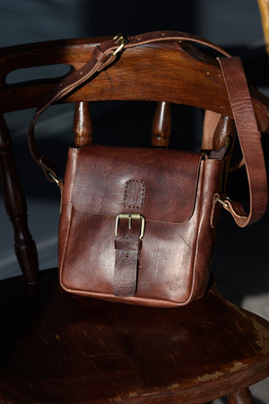 close-up photo of brown messanger leather bags on a wooden chairの写真素材