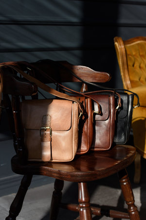 close-up photo of colorful messanger leather bags on a wooden chairの写真素材