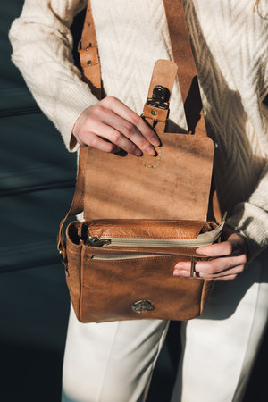 beautiful woman posing with a empty small brown bag near grey wallの写真素材