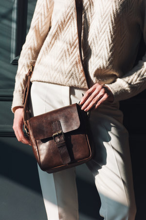 beautiful woman posing with a small brown bag near grey wallの写真素材