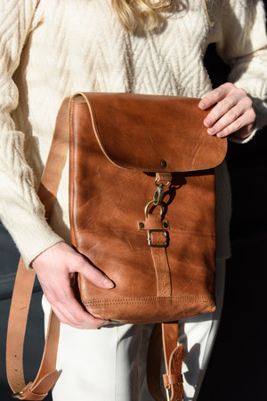 beautiful woman posing with a empty small brown bag near grey wallの写真素材
