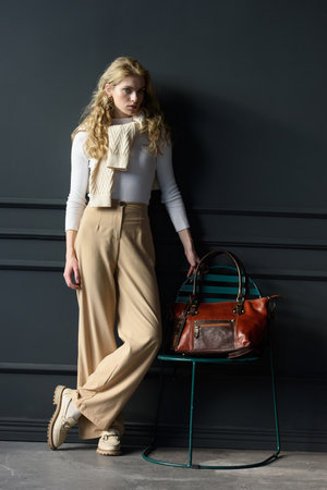 beautiful curly blond hair woman posing with a brown shopper bag near gray wallの写真素材