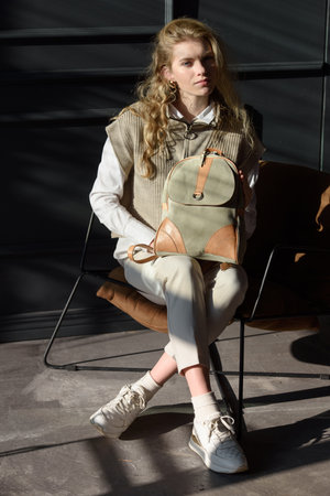 beautiful curly blond hair woman posing with a leather backpackの写真素材