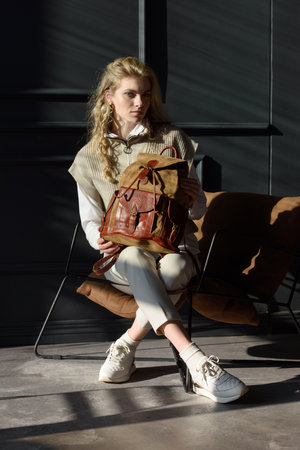beautiful curly blond hair woman posing with a leather backpackの写真素材