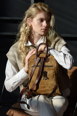 beautiful curly blond hair woman posing with a leather backpackの写真素材