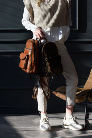 beautiful curly blond hair woman posing with a two leather backpacksの写真素材