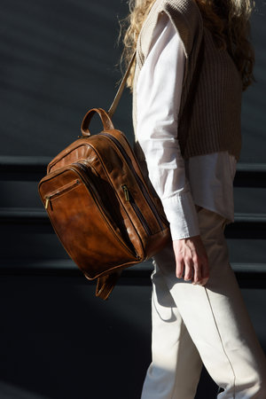 beautiful curly blond hair woman posing with a leather backpackの写真素材