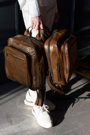 beautiful curly blond hair woman posing with a two leather backpacksの写真素材