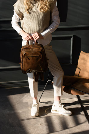 beautiful curly blond hair woman posing with a leather backpackの写真素材