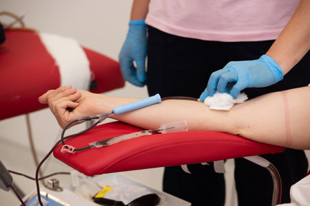 Laboratory and blood analysis concept. Close up cropped shot of professional nurse in gloves, taking a blood sample from arm vein of young female patientの写真素材