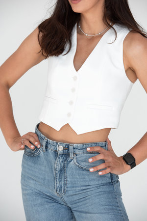 Happy beautiful girl posing in a new hot summer look. Wearing blue jeans and white waistcoatの写真素材