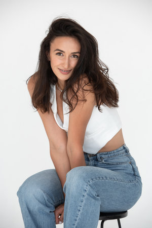 Happy beautiful girl posing in a new hot summer look. Wearing blue jeans and white waistcoatの写真素材