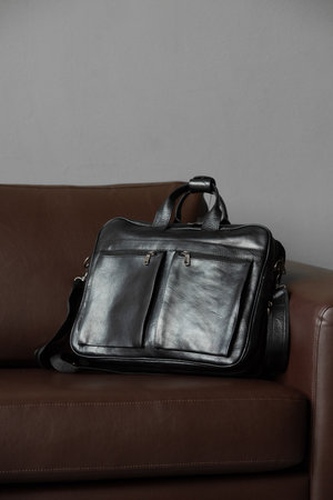 A sleek black briefcase on a cozy brown couchの写真素材