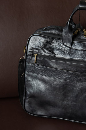 A sleek black briefcase on a cozy brown couchの写真素材