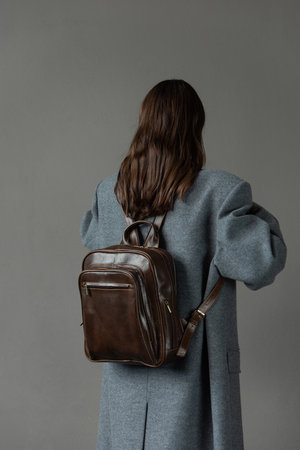 woman posing with a leather backpack wearing a warm gray coatの写真素材