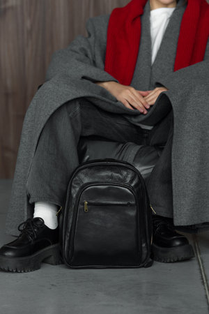 woman posing with a leather backpack wearing a warm gray coat and black shoesの写真素材