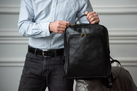 A Stylish and Professional Man Standing with a Bag in a Contemporary Modern Settingの写真素材