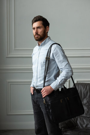 A Stylish and Professional Man Standing with a suitcase. Wearing blue shirt and black jeansの写真素材
