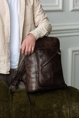 A Stylish and Professional Man Standing with a brown backpack in a Contemporary Modern Setting.の写真素材
