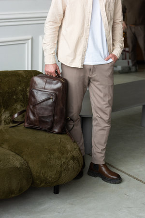 A Stylish and Professional Man Standing with a brown backpack in a Contemporary Modern Setting.の写真素材