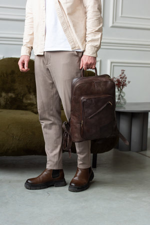 A Stylish and Professional Man Standing with a brown backpack in a Contemporary Modern Setting.の写真素材