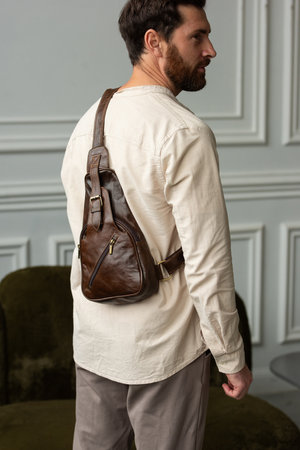 A Stylish and Professional Man Standing with a brown hip pack in a Contemporary Modern Setting.の写真素材