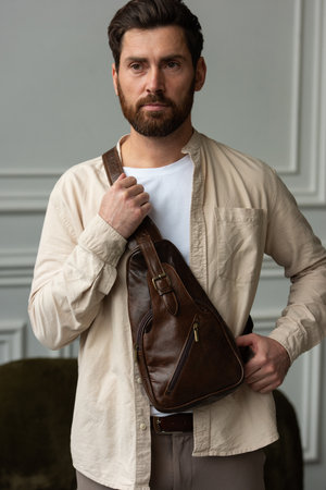 A Stylish and Professional Man Standing with a brown hip pack in a Contemporary Modern Setting.の写真素材
