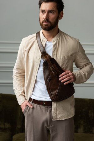A Stylish and Professional Man Standing with a brown hip pack in a Contemporary Modern Setting.の写真素材