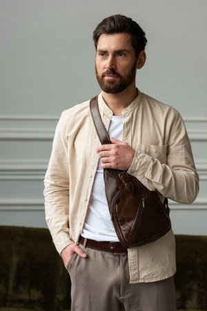 A Stylish and Professional Man Standing with a brown hip pack in a Contemporary Modern Setting.の写真素材