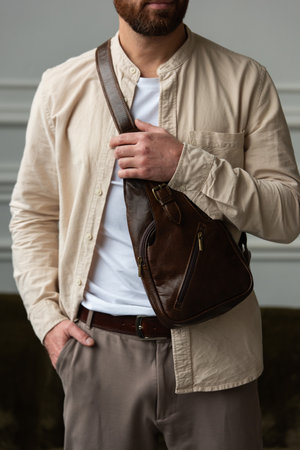 A Stylish and Professional Man Standing with a brown hip pack in a Contemporary Modern Setting.の写真素材