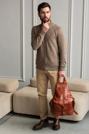 A Stylish and Professional Man Standing with brown yellow backpack in a Contemporary Modern Settingの写真素材