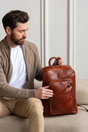 A Stylish and Man sitting with a yellow brown backpack in a Contemporary Modern Settingの写真素材