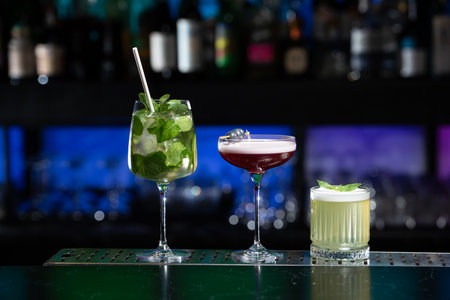 row of various colourfull alcoholic cocktails on a bar desk. Glasses of differen shapes. selective...