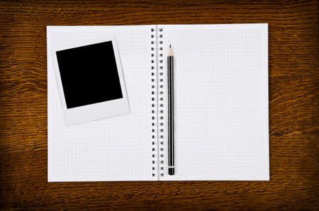 Classic instant photo frame on blank notebook with pencilの写真素材