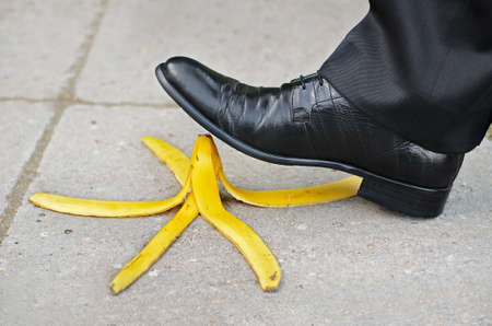 Businessman about to slip and fall on a banana skin の写真素材