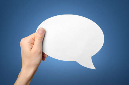 Hand holding an empty speech bubble on blue 