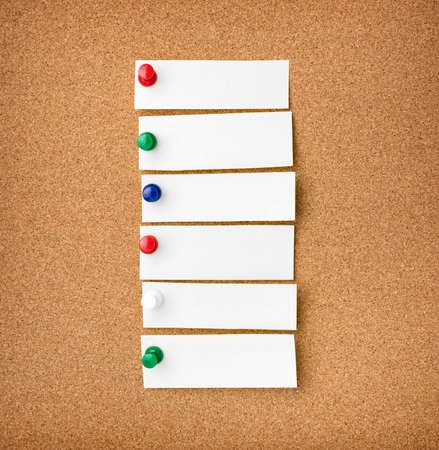 Close up front view of illustrative corkboard with blank white note cards pinned with colorful pins,...