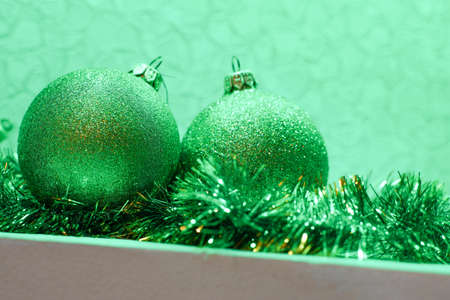 Green shiny christmas balls lie on green tinsel, close-up in green lightingの写真素材