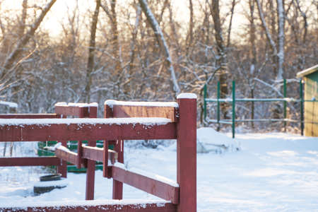 Winter rural landscape, in the background a snowy forest, in the foreground a red wooden fenceの写真素材