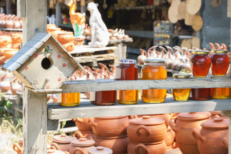 Street market in Georgia. Clay pots and other products are on display in the background, and glass jars of honey are in the foreground.の写真素材