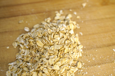Oatmeal opens in a pile on a wooden cutting boardの写真素材