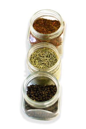 Three jars with spices: rosemary, paprika, black pepper. Isolated photo with shadowの写真素材