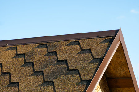 View of the metal roof ridge. The roof is covered with soft tilesの写真素材