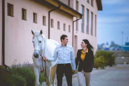 Man and woman with the white horse look on each others and go on the horses club backgroundの写真素材